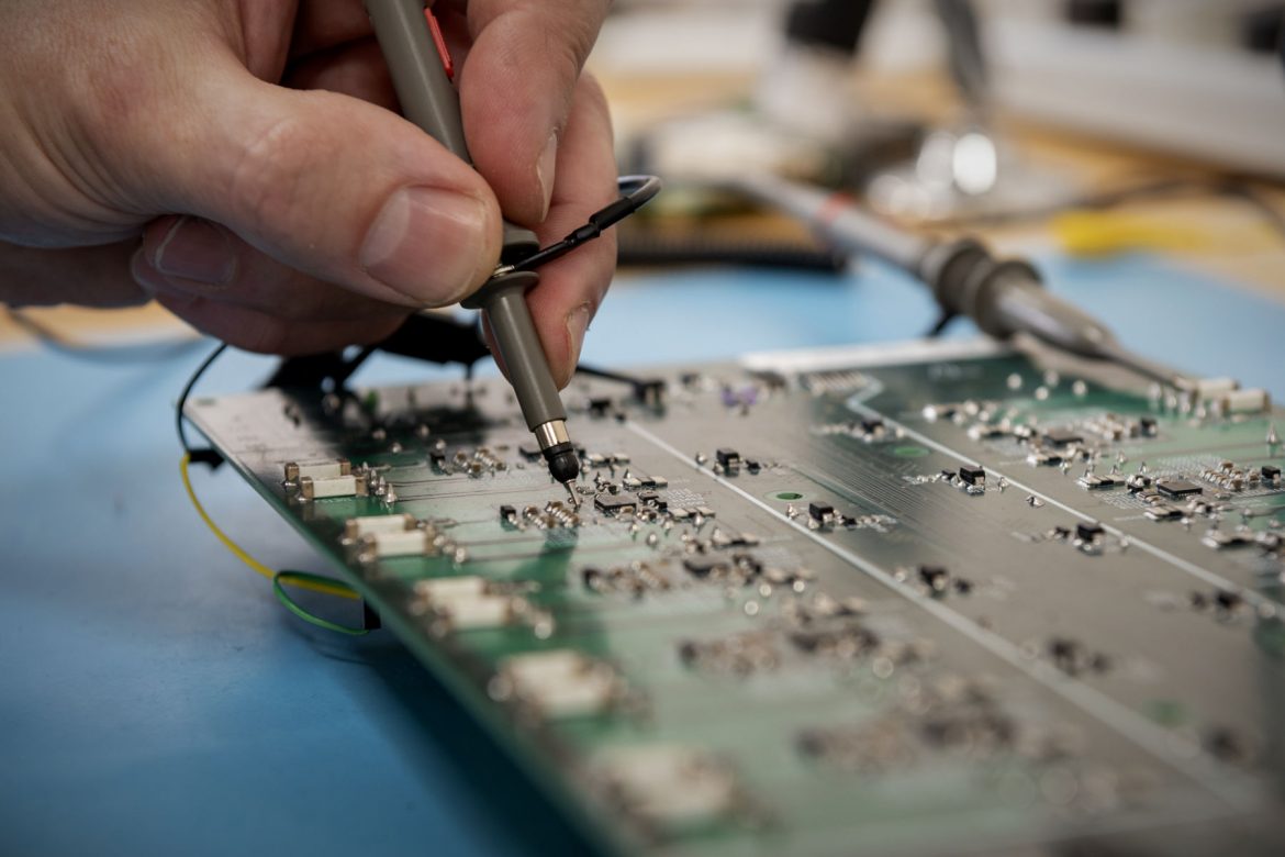 Close up of oscilloscope probe measuring signals on PCB during testing