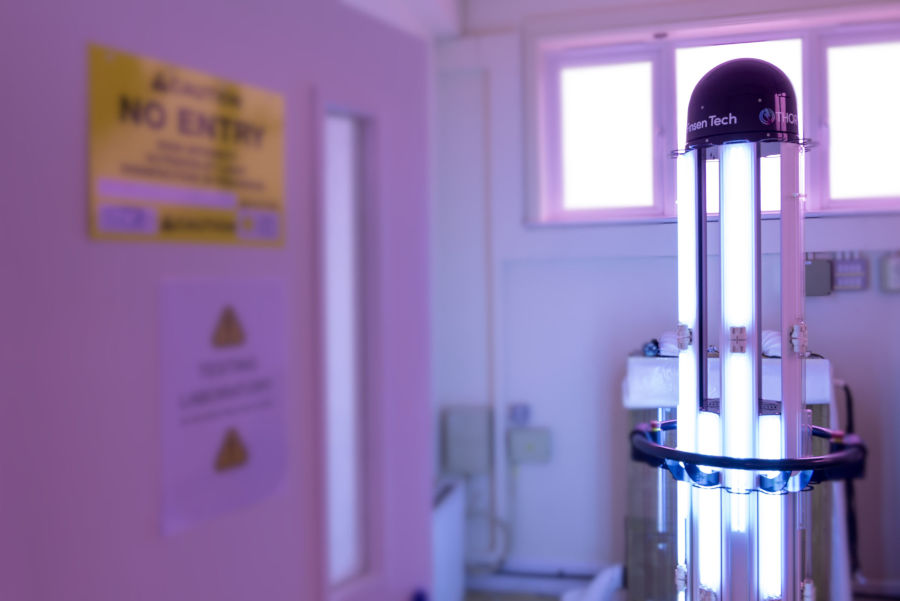 UVC disinfection tower illuminating testing lab in purple light