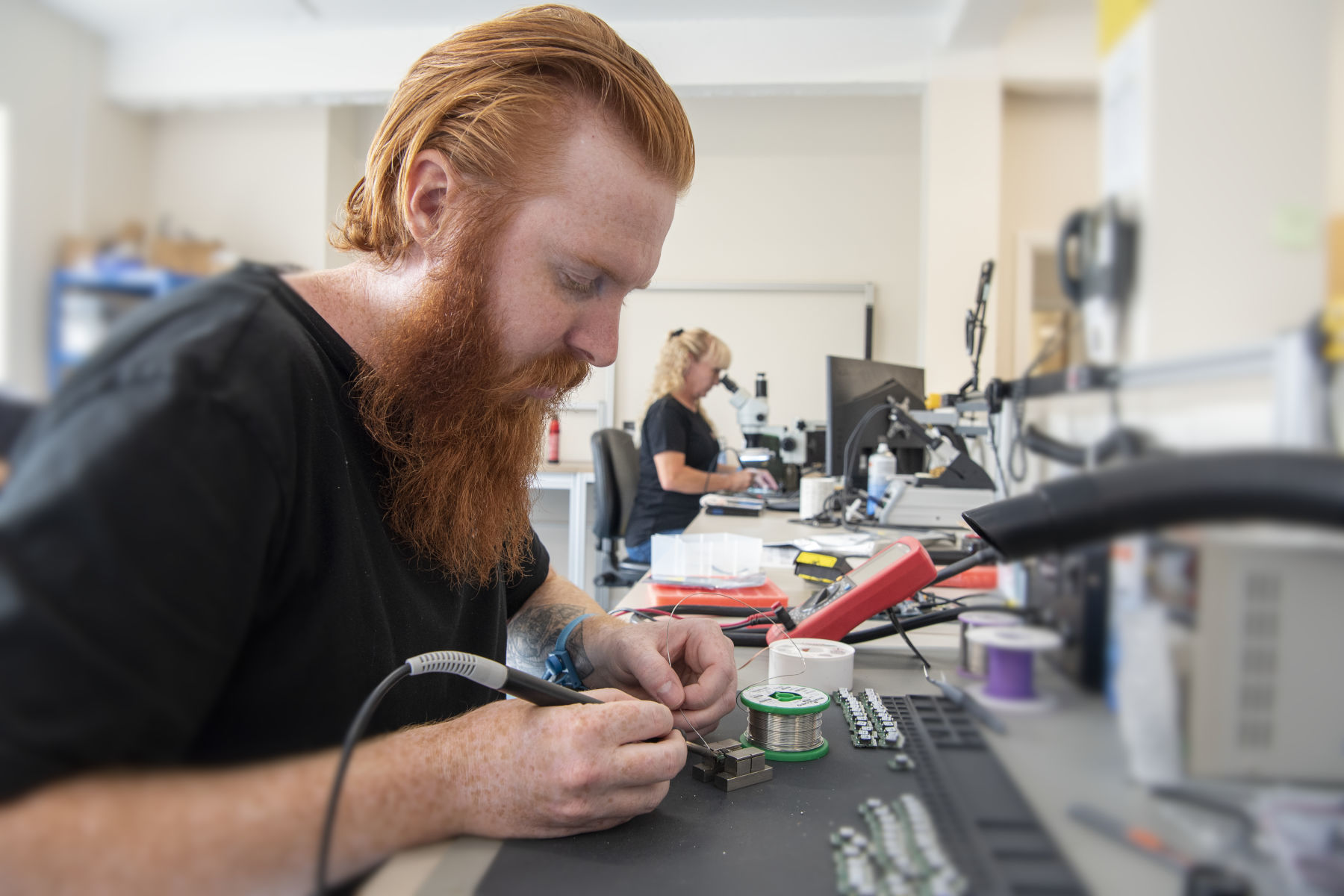 Electronics technician hand soldering surface mount components onto a PCB assembly