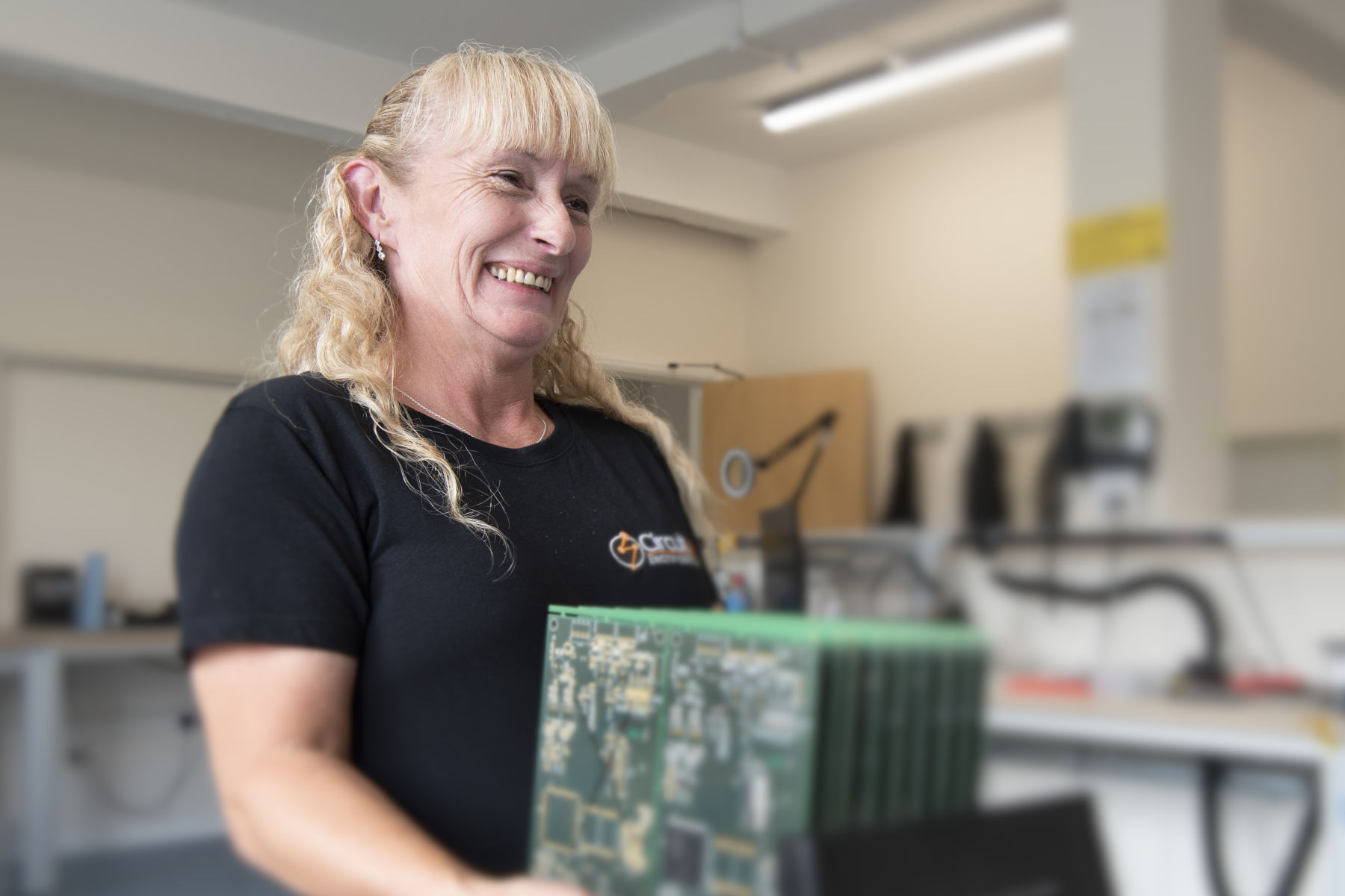 Electronics assembly technician carrying rack of assembled PCBs