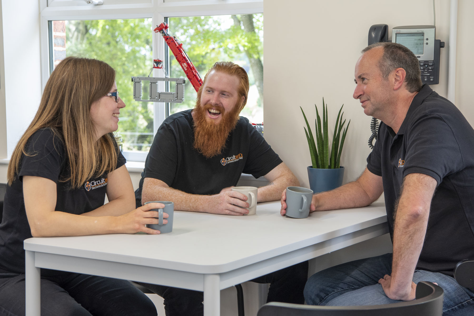 Three CircuitWorx employees drinking coffee and laughing together